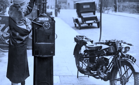 A lady fills a vintage motorcycle in a very old picture