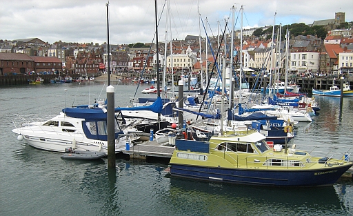 scarborough harbour with boats, the surrounding shops and hotels and on the hill st mary's church