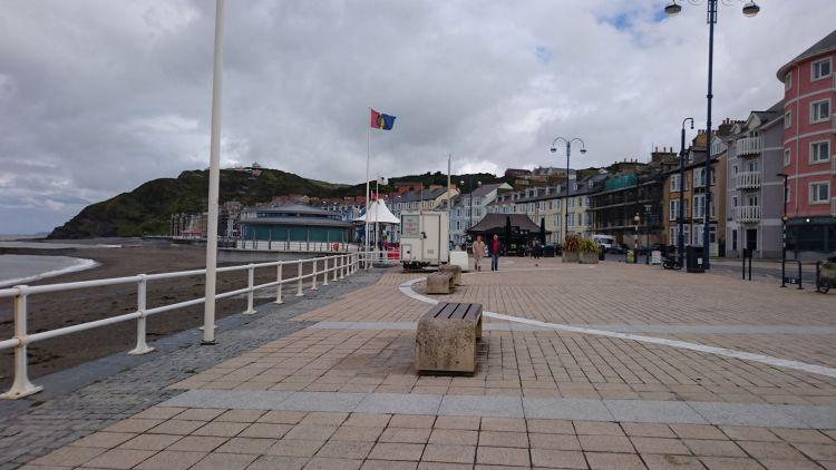 The sweeping curve of Aberystwyth promenade, a beach, hills and a broad footpath