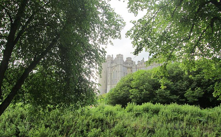 The towering walls of Arundel Castle seen between trees and shurbs