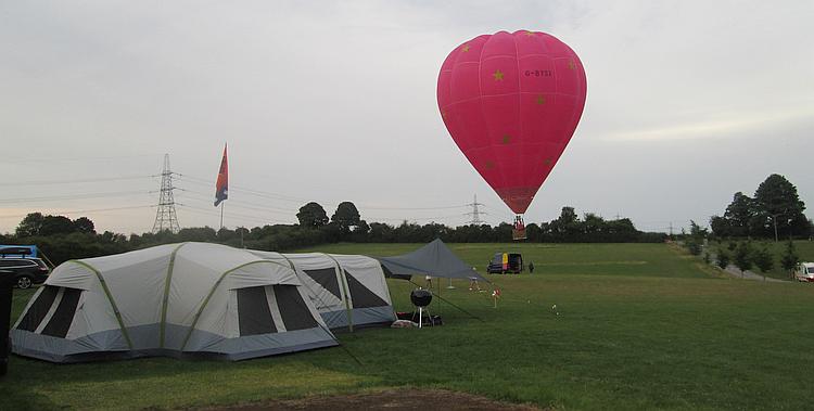 A large red hot air balloon leave the campsite at Far Peak