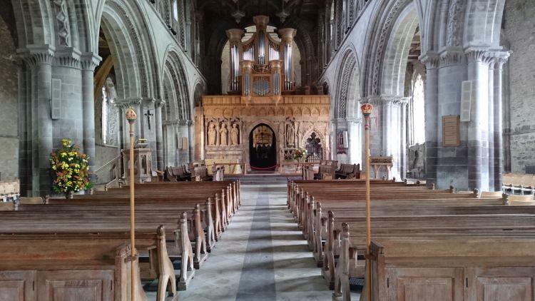 Columns and woodwork and a massive organ and pews inside St Davids Cathedral