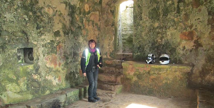 Sharon stands in the chapel, stone walls, stone seat and stone alter