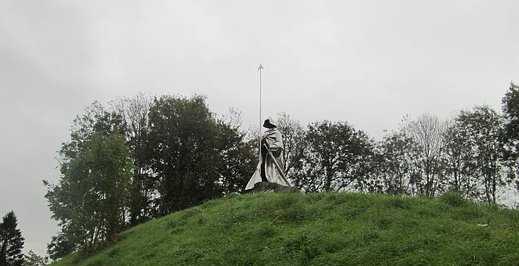 The shiny steel statue stands tall on a hill