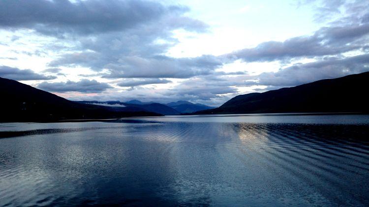 The skies are huge and many shades of blue across a still Loch Broom at Ullapool