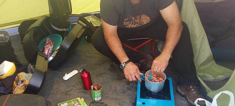 Pete's stirring a pan of pasta and hot dog sausages in the tent