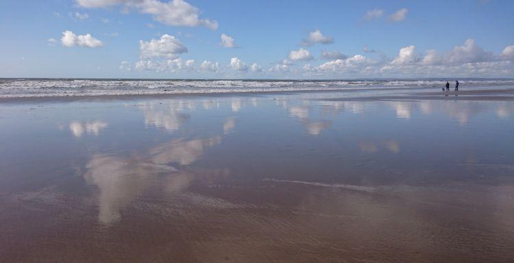 The sky is reflected on the wet sands at Rhossili Beach