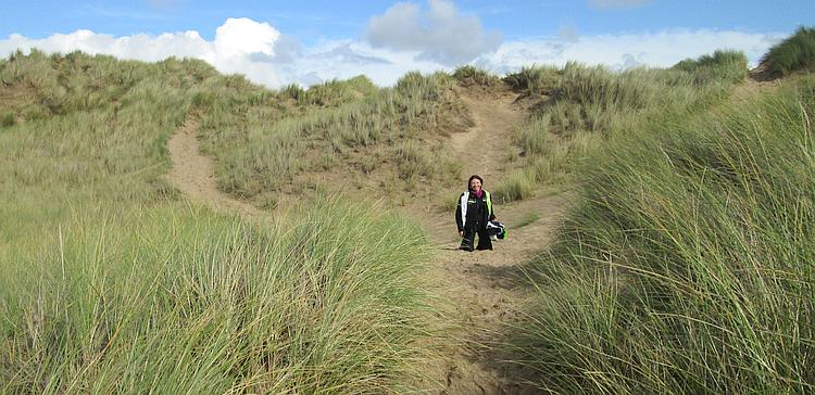 Sharon's on her knees in the sandy dunes as we head to the beach