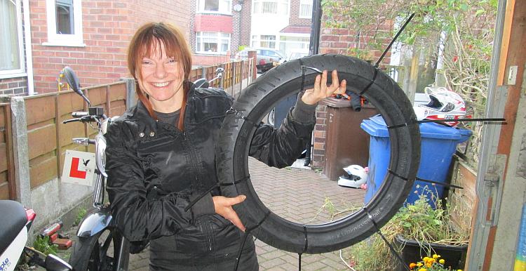 Sharon holds a motorcycle tyre with zip ties around it