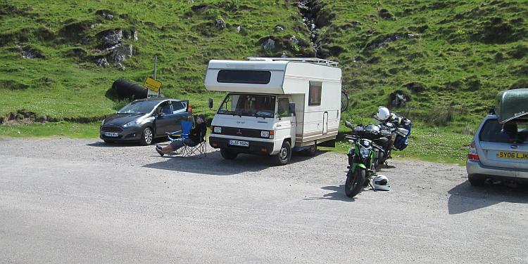 Several cars, a motorhome and motorcycles at a layby on the NC500 route