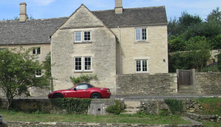 A large stone house with a sports car outside