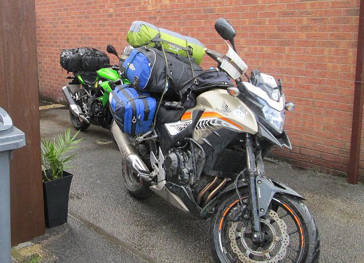 The 2 motorcycles buckling under a mound of luggage, ready for the forthcoming adventure