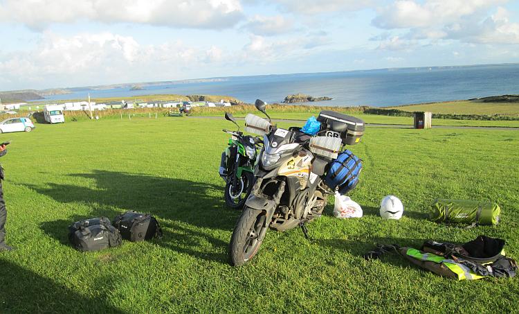 The motorcycles and the camping kit spread out with the vast bay behind