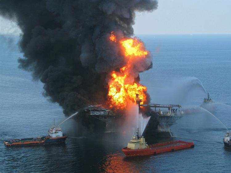 stock photo of a massive oil fire on a rig with ships trying to put it out