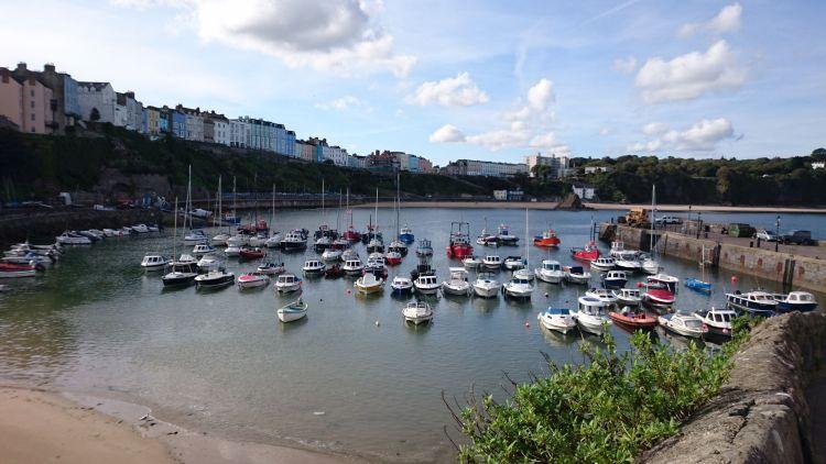 Small boats fill the curved harbour in sun filled Tenby