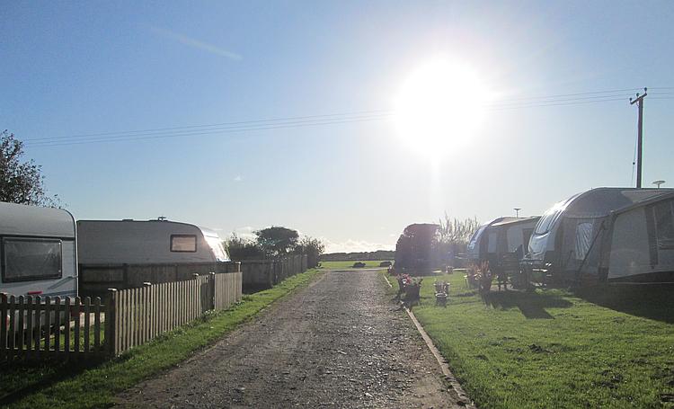 Bright low sunshine over caravans and blue skies at the camp site