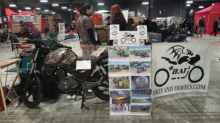 The stand with a table, a motorcycle and a BAT banner separating Sharon and Ren from the punters
