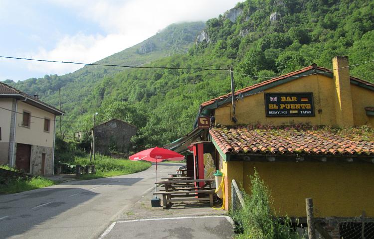 A light brown Spanish bar with vast steep tree covered hills in the background at Puente de Vega