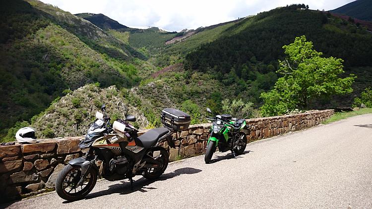 The Honda and the Kawasaki on a mountainside road overlooking dramatic angular mountains 