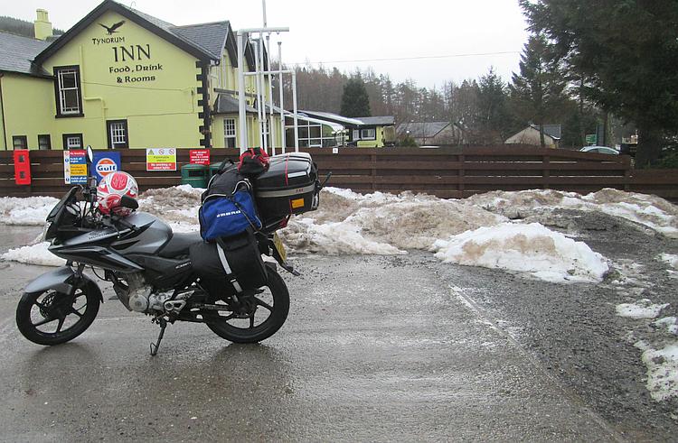 The CBF 125 with camping gear at Tyndrum in Scotland with piles of snow in the car park