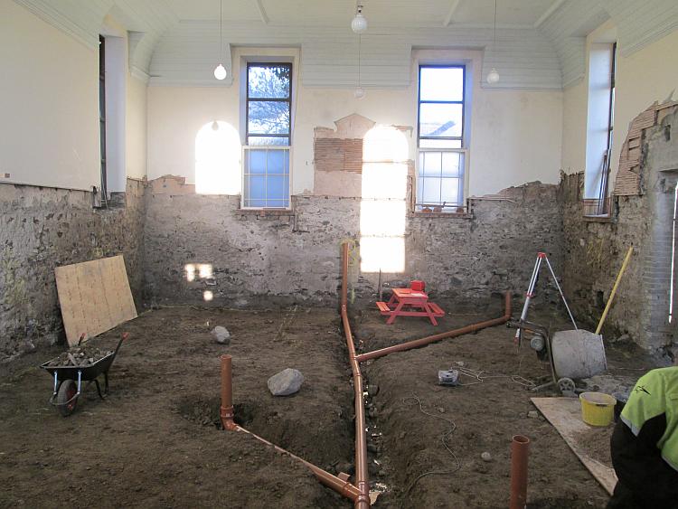 The inside of the large old chapel has the floor up and sewage pipes installed
