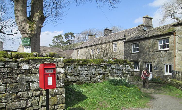 A stone farmhouse, trees and sunshine in the village of Keld