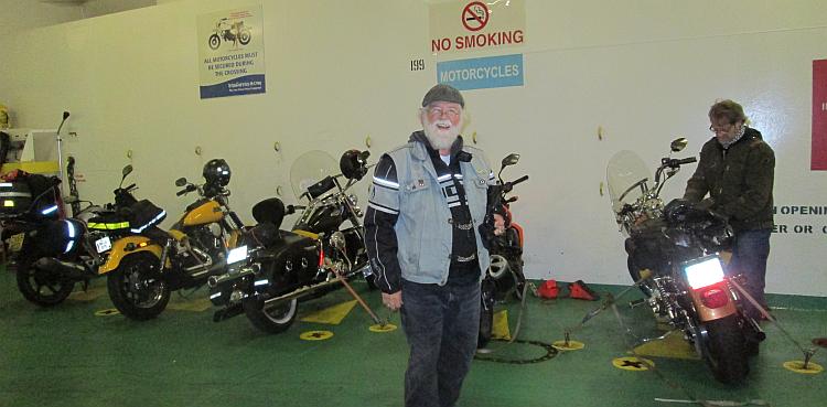7 or 8 motorcycles lined up in the hold of the Ferry to Ireland with a biker smiling at the camera