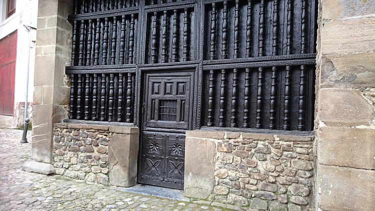 A wooden carved and turned doorway and door all painted black at Potes