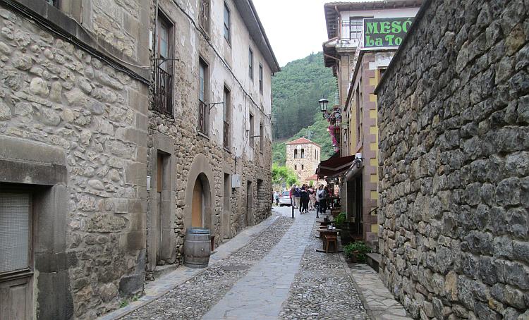 A narrow lane with shops and people in Potes