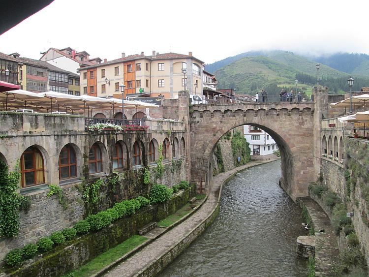 The river cuts through the town with tall steep stone walls and a stone bridge