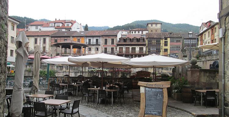 Tables, chairs and parasols on the small cobbled street of potes