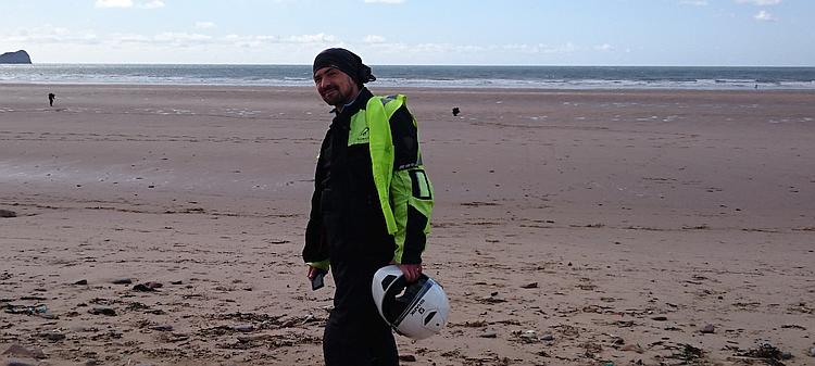 Ren grins at the camera against the backdrop of the cast sands and ocean at Rhossili