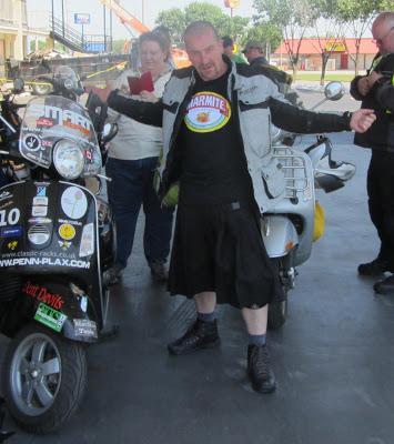 Stephen is posing in his black kilt next to the Vespa