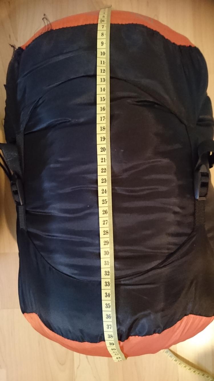 The packed sleeping bag next ot a tape measure