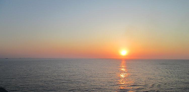 A deep orange sunset across the flat ocean of The Bay Of Biscay