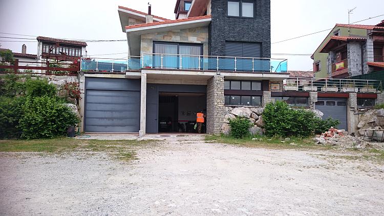 A modern looking Spanish house has a garage underneath it as Ren walks inside