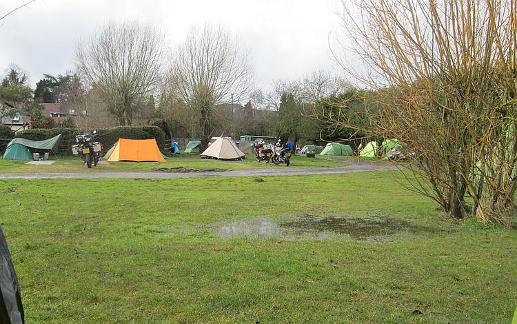 The waterlogged field has a large puddle between Ren's tent and the track to the pub
