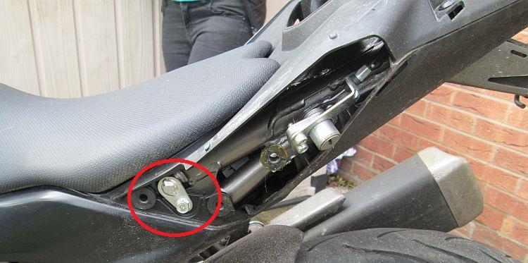 The rear subframe of the bike is now exposed and the seat fixing pins are circled