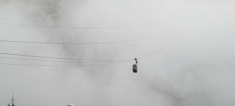 A solitary cable car gondola rises into the clouds at Fuenta De
