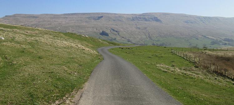 An empty tarmac lane winds across the hills of North Yorkshire