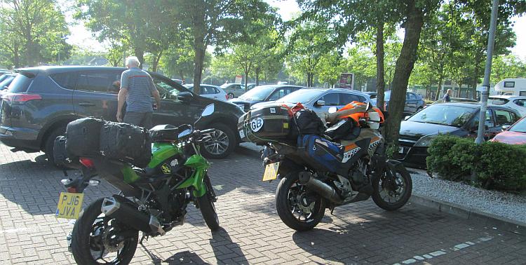 Ren and Sharon's bikes under a pile of luggage in the car park of the motorway services