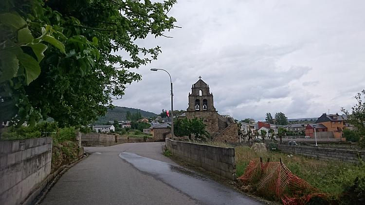 A small spanish church with bells amidst ordinary spanish houses
