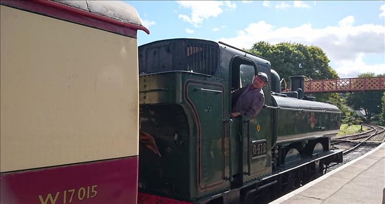 The driver of the steam engine leans out to ensure everyone is on the carriages