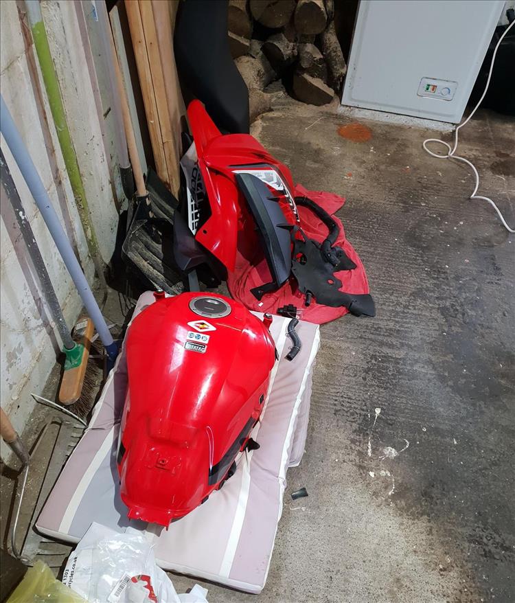The bright red panels of the CB500x carefully stored on the garage floor