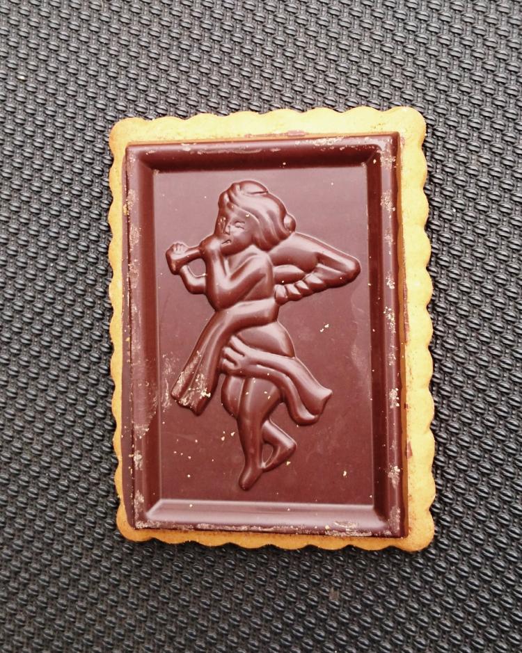 A chocolate covered biscuit with an angel playing a pipe moulded into the chocolate