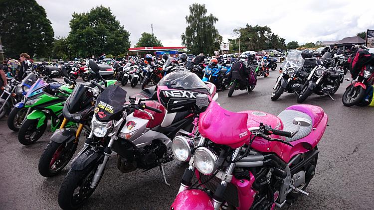 A range of motorcycles fill the car park in the rain at the Truck Stop