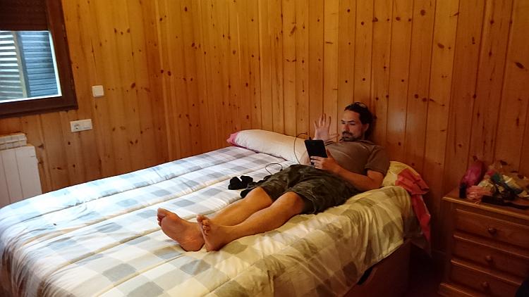 Ren relaxing on the double bed of the wooden lodge