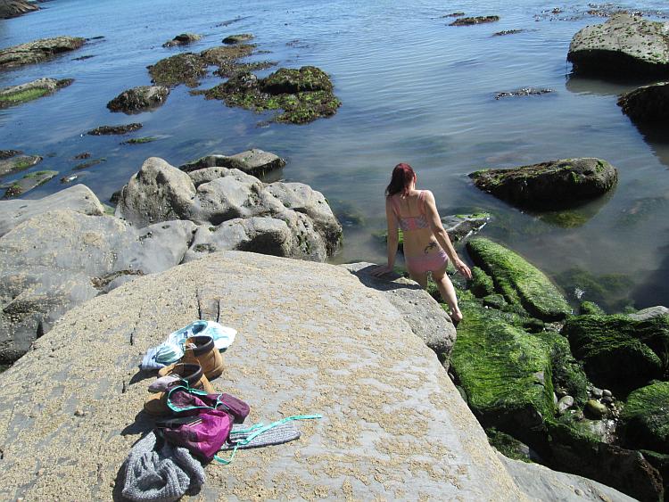 Sharon in her underwear is climbing down the coastal rocks into the sea at Devon