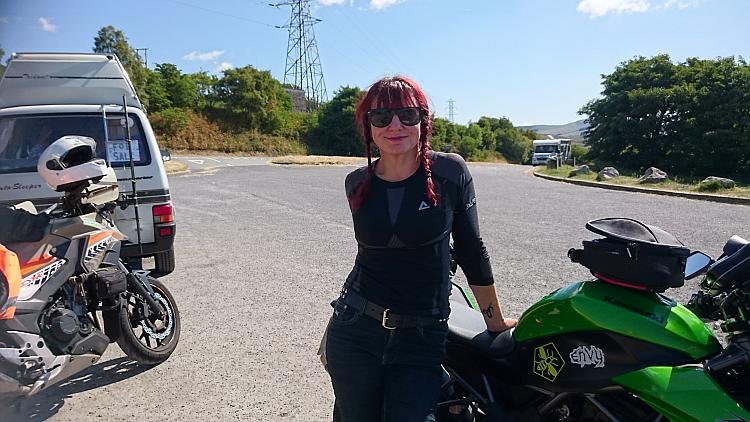Sharon stands by her bike smiling in the glorious sun on a ride out through Wales