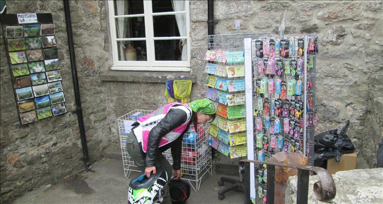 Sharon picking up her bike gear amidst postcards and keyrings outside a local shop